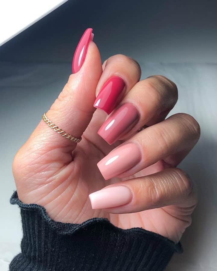 Hand with long square nails in mixed pink shades ranging from soft nude to deep rose, featuring a glossy finish for a simple and polished manicure.