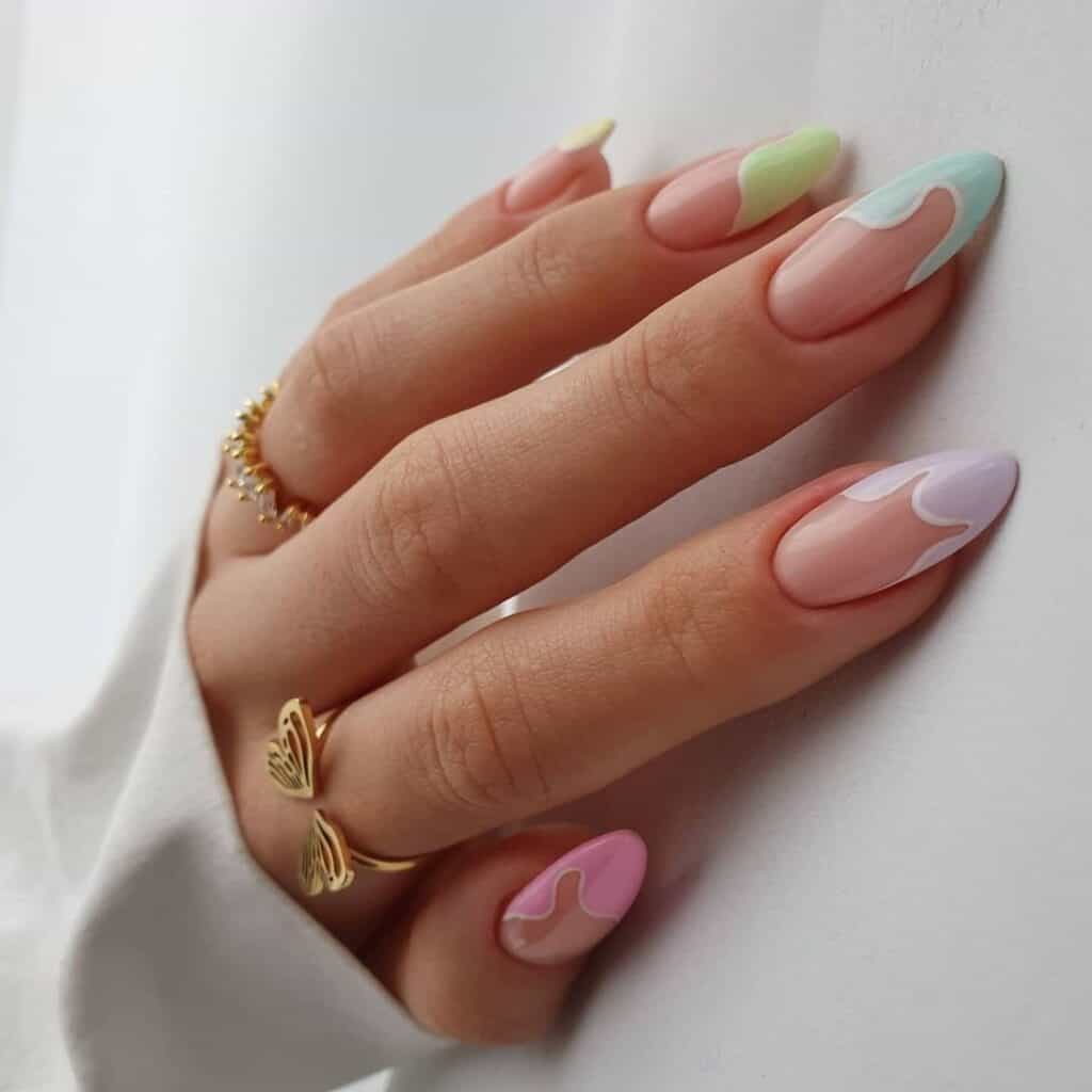 Hand with almond shaped nude nails featuring soft pastel wavy French tips in mint, lavender, pink, and yellow, creating a light and playful spring inspired manicure.
