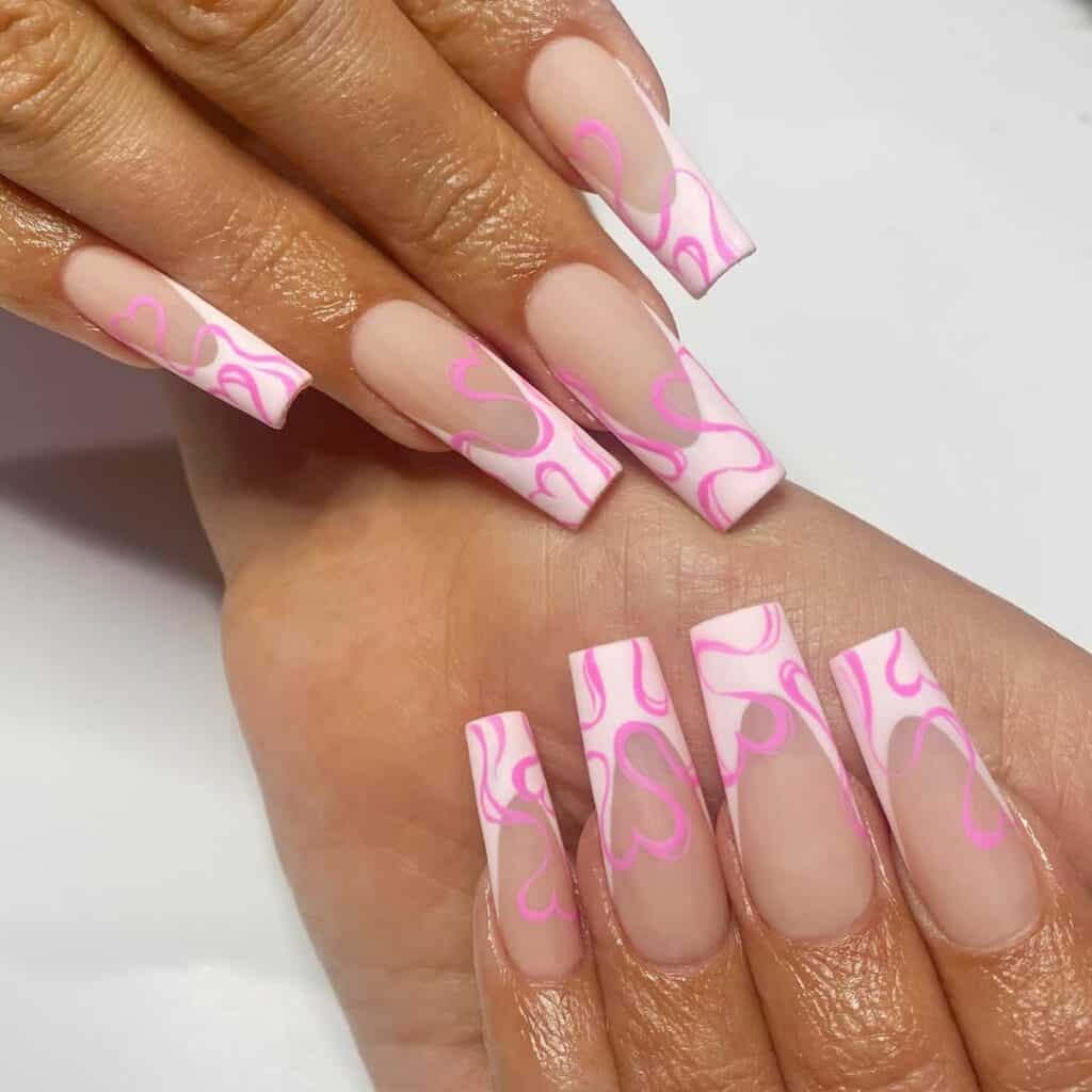 Both hands with long square nude nails featuring pink abstract swirl and heart outlines over milky tips, creating a bold and modern Valentine’s inspired manicure.